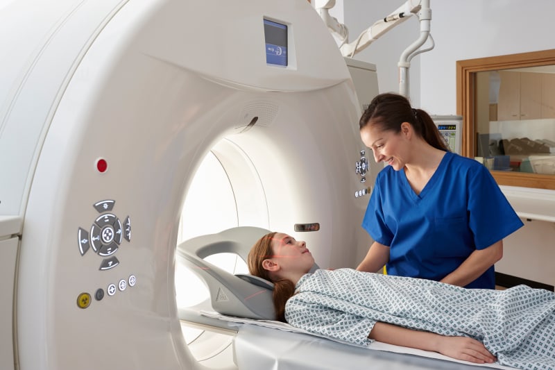 Radiographer reassuring girl going into CT scanner.