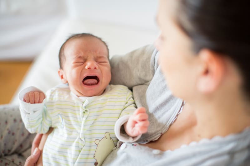 A mother holding a crying baby.