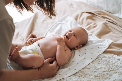 Mother leaning over infant laying on a blanket
