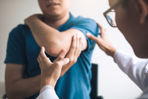 Specialist looking at man's elbow