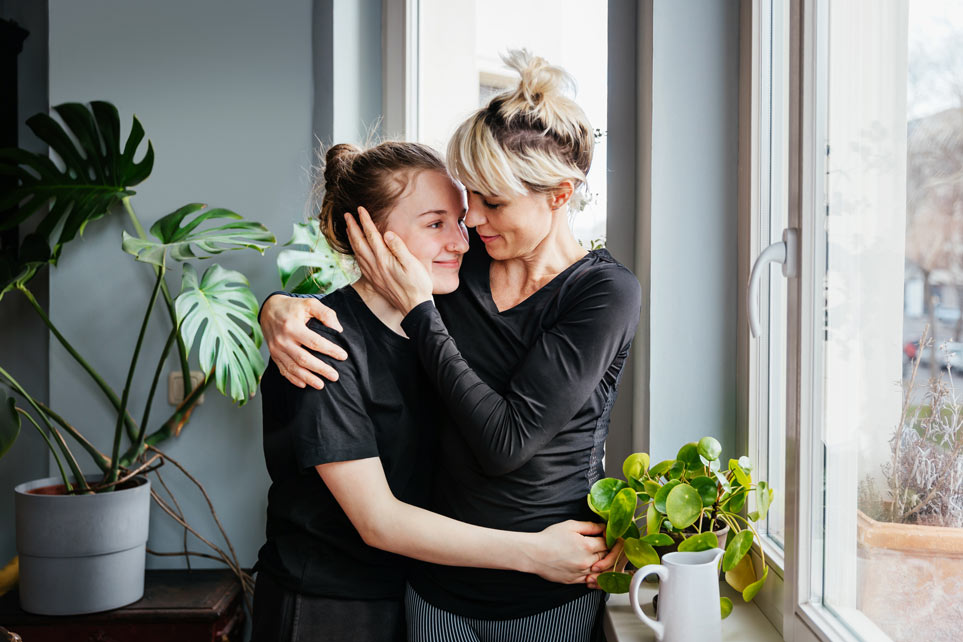 Single mom affectionately hugging teenage daughter.