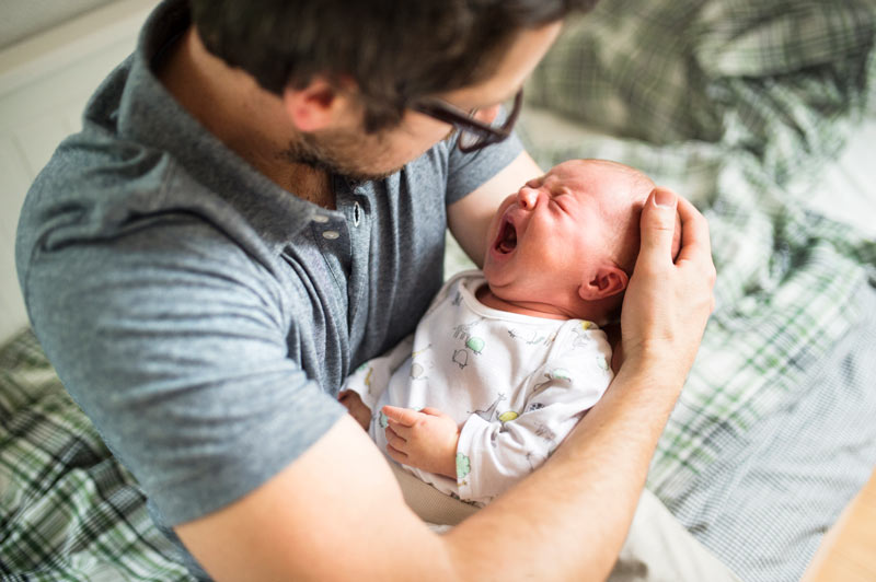 Father at home consoling his crying baby daughter.